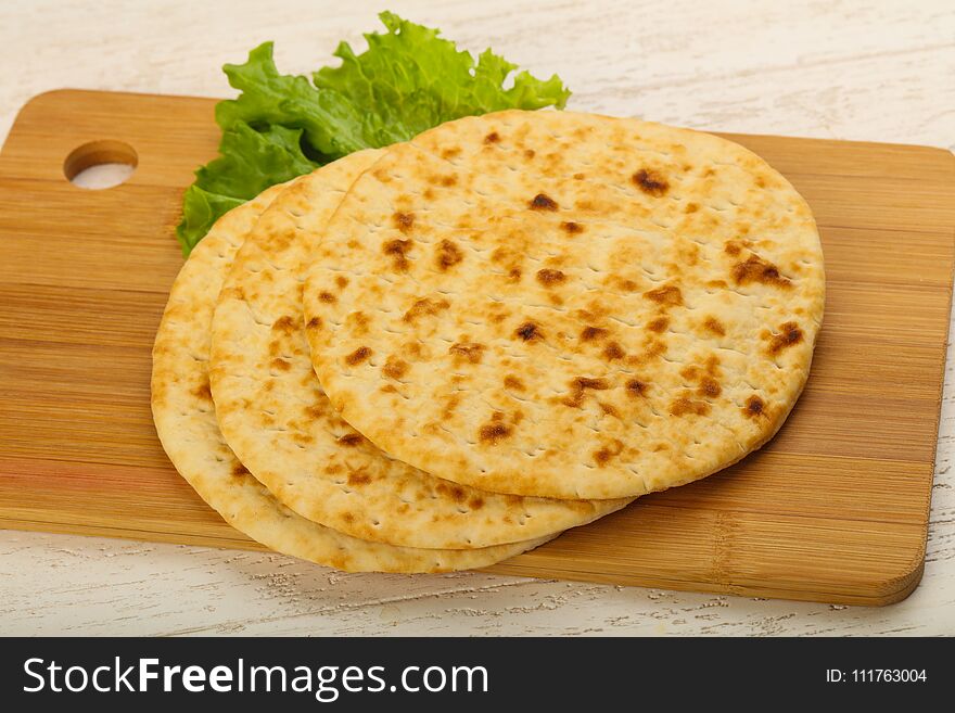 Pita bread with salad over wood background