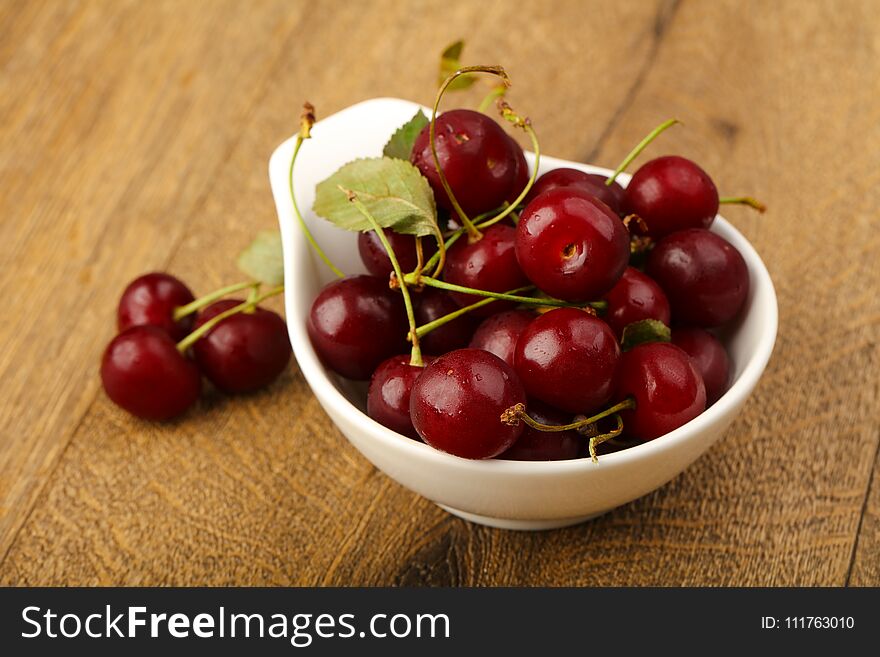 Cherry berries in the bowl on wood background