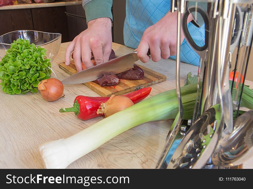 Cook hands with raw meat and vegetables in kitchen. Butcher cutting meat on kitchen