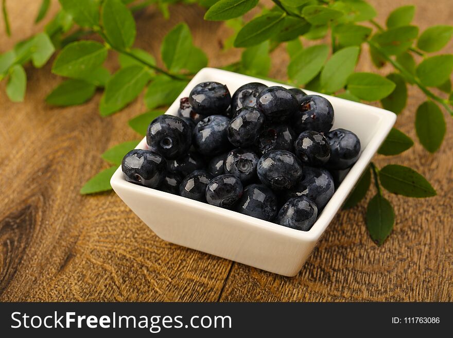 Ripe Blueberry heap with leaves on wood background