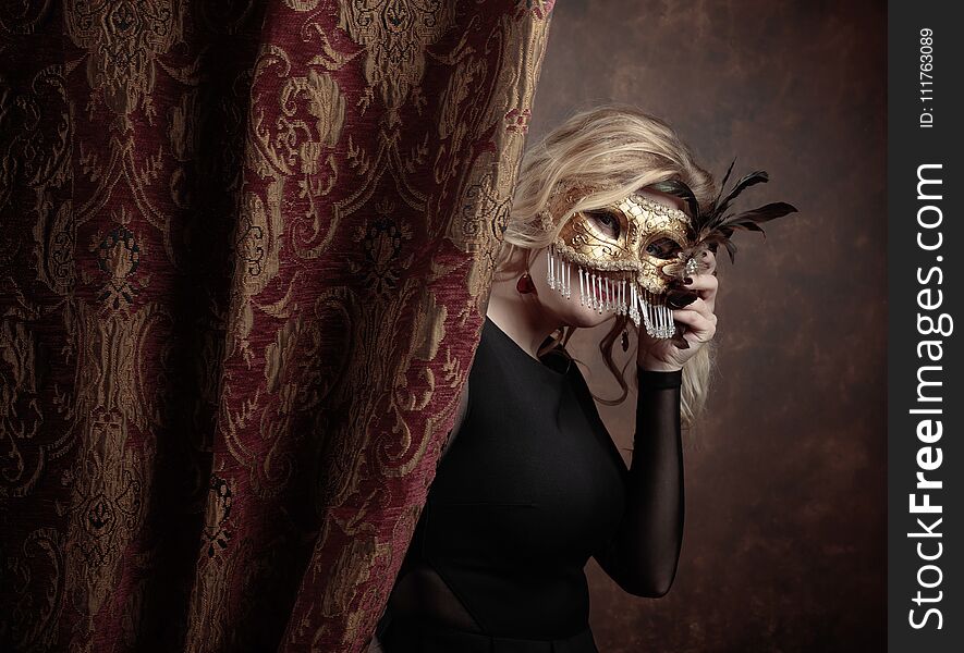 Portrait of beautiful young woman with carnival mask. Gorgeous hair and natural makeup. Fashion beauty photo. Natural blonde in black dress. Portrait of beautiful young woman with carnival mask. Gorgeous hair and natural makeup. Fashion beauty photo. Natural blonde in black dress.