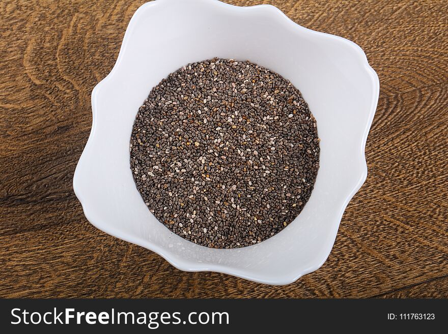 Chia seeds heap in the bowl over wood background