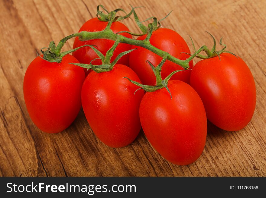 Fresh ripe juicy Tomato branch on the wood background