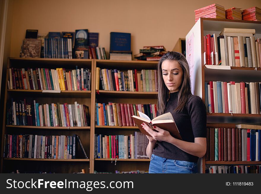 Woman studying in library, standing and reading book.