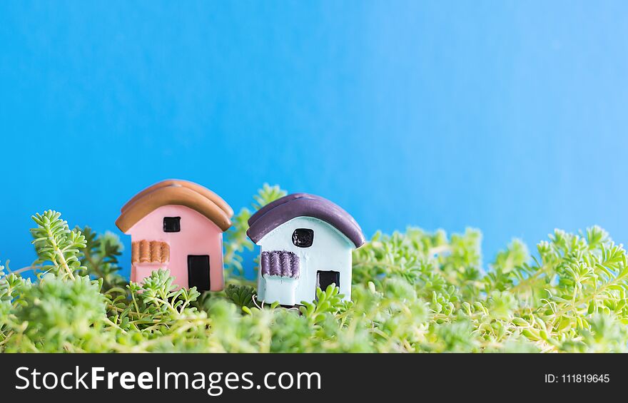 Two toy houses on the grass on a blue background. The concept of building a new home.