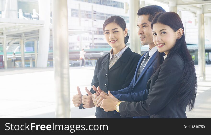 Group of business people of men and women stand and thumb up together in the feeling of happy and success at the outdoor pedestrian walk way. Group of business people of men and women stand and thumb up together in the feeling of happy and success at the outdoor pedestrian walk way