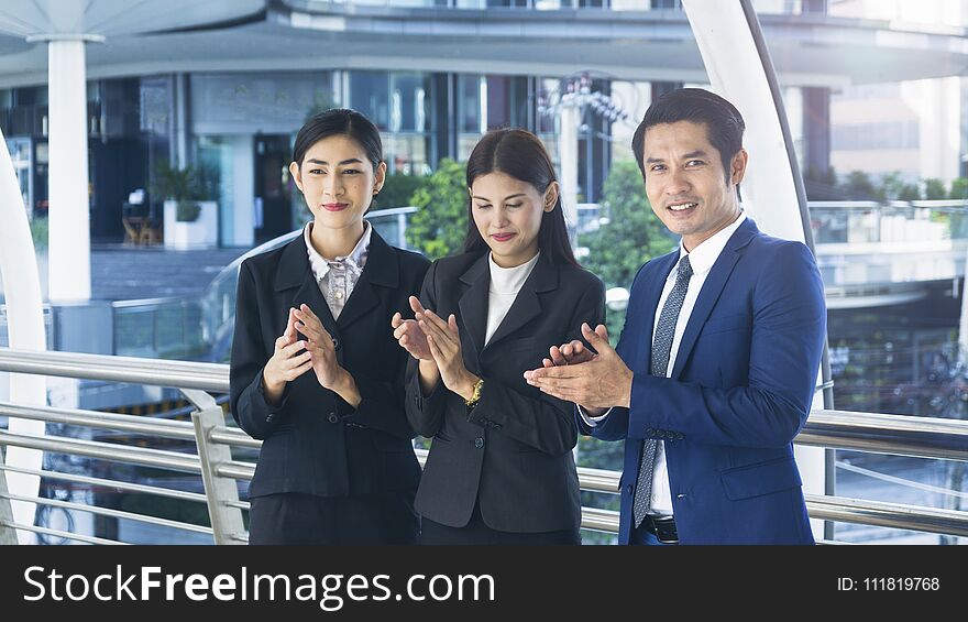 Group of smart people of men and women stand and clap hands in the feeling of happy and success at the outdoor pedestrian walk way. Group of smart people of men and women stand and clap hands in the feeling of happy and success at the outdoor pedestrian walk way
