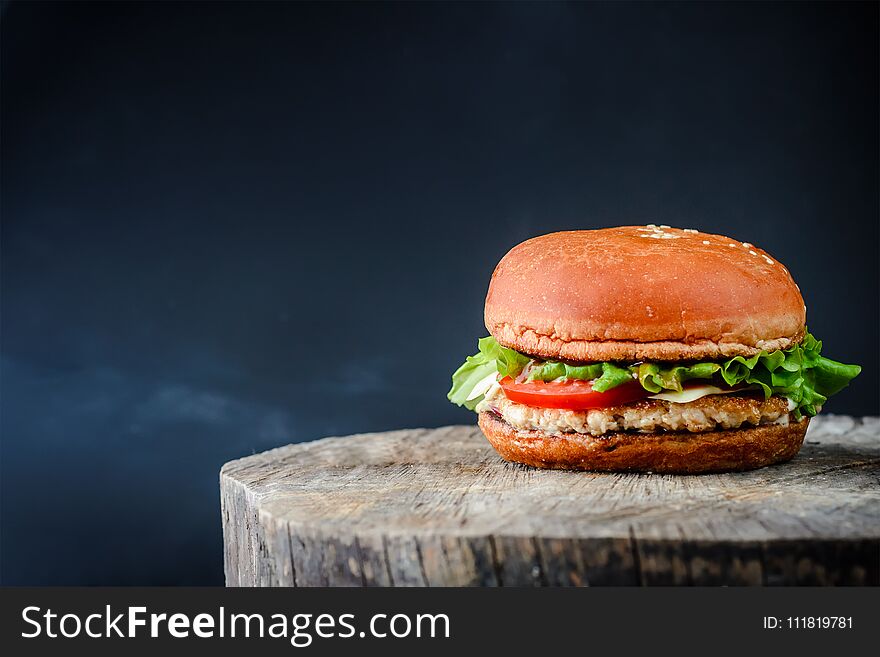 Appetizing burger on a wooden table on a dark background with copy space. Appetizing burger on a wooden table on a dark background with copy space