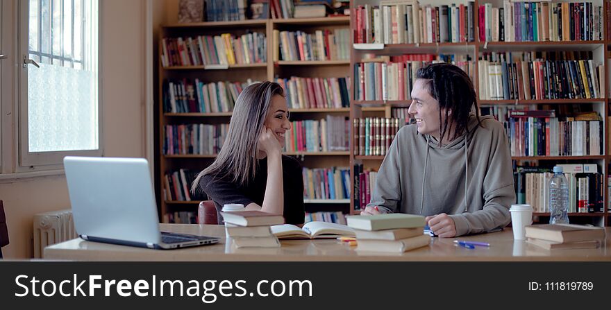 Female and male student in library, learning and laughing. Female and male student in library, learning and laughing.