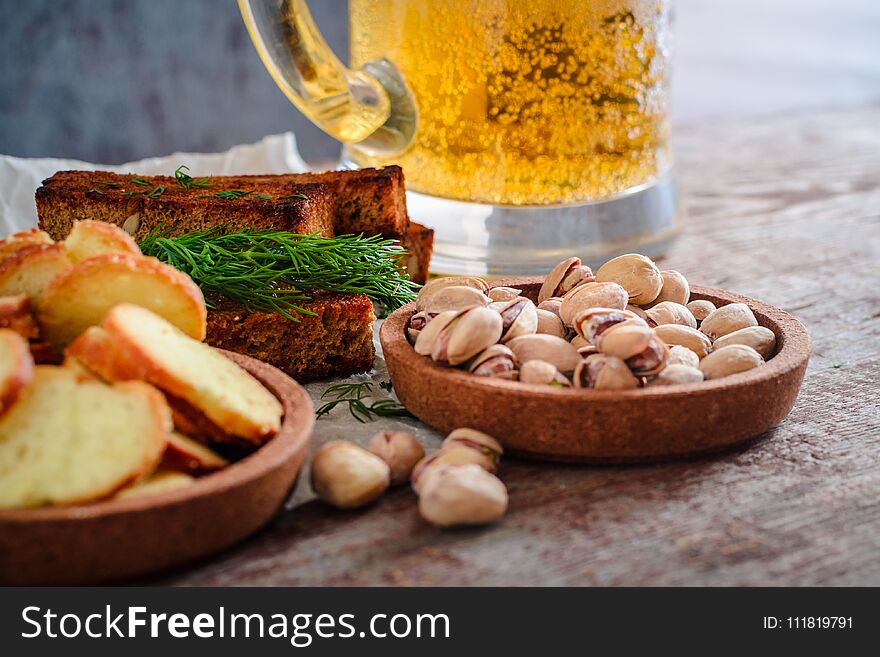 A glass of light beer, pistachios and rusks on a wooden table. A glass of light beer, pistachios and rusks on a wooden table