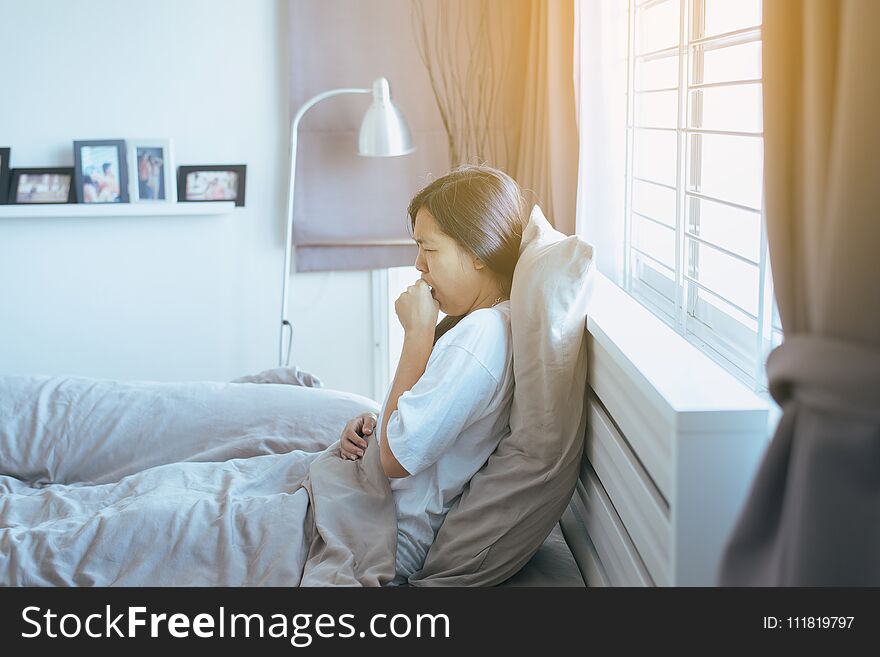 Young asian woman coughing and sitting on her bedroom,Concept of health