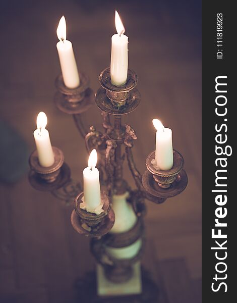 Antique silver candlestick standing on the table in the dark room. Red flames visible