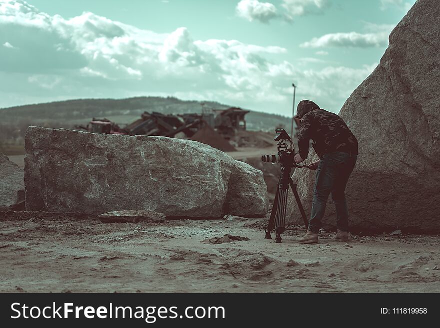 Video camera operator working with his video equipment in the stone quarry during day time.