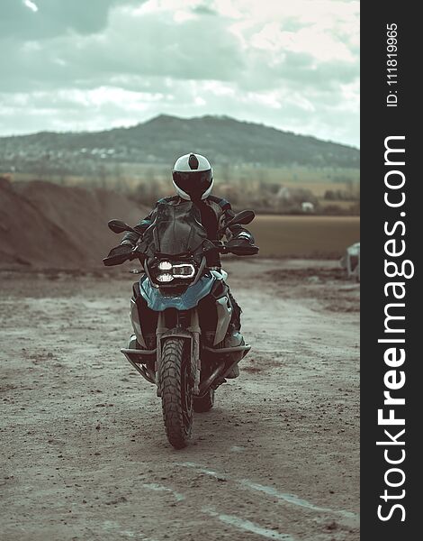 Motorcyclist with helmet and motorbike outfit riding on the modern motorbike. Beautiful mountains visible in the background.