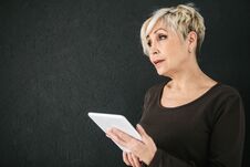 A Successful Positive Modern Elderly Woman Holds A Tablet In Her Hands And Uses It. The Older Generation And Modern Royalty Free Stock Photography A Successful Positive Modern Elderly Woman Holds A Tablet In Her Hands And Uses It. The Older Generation And Modern Royalty Free Stock Photography