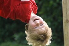 Happy Laughing Boy Hanging Upside Down In A Playground Stock Photo