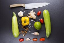 Vegetables And Knife On Black Ceramic Table. Ingredients For Cooking. Zucchini, Peppers, Tomatoes, Garlic, Lime, Nuts And Salt Royalty Free Stock Photos