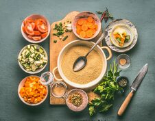 Couscous And Vegetarian Cooking Ingredients In Bowls On Cutting Board With Spoon , Gray Background Royalty Free Stock Image