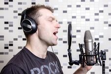 A Young Guy Singer And Rock Musician Sings In A Studio Condenser Microphone In Headphones In A Recording Studio Stock Image