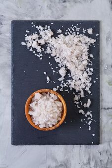 Large White Sea Salt In A Natural Wooden Bowl On Dark Board Over Lifgt Background, Top View, Close-up, Selective Focus Stock Photo