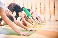 Group Of People Doing Yoga Downward Facing Dog Pose On Mats At Studio Stock Images