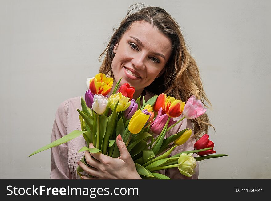 Young charming girl with a bouquet of flowers - multi-colored tulips.