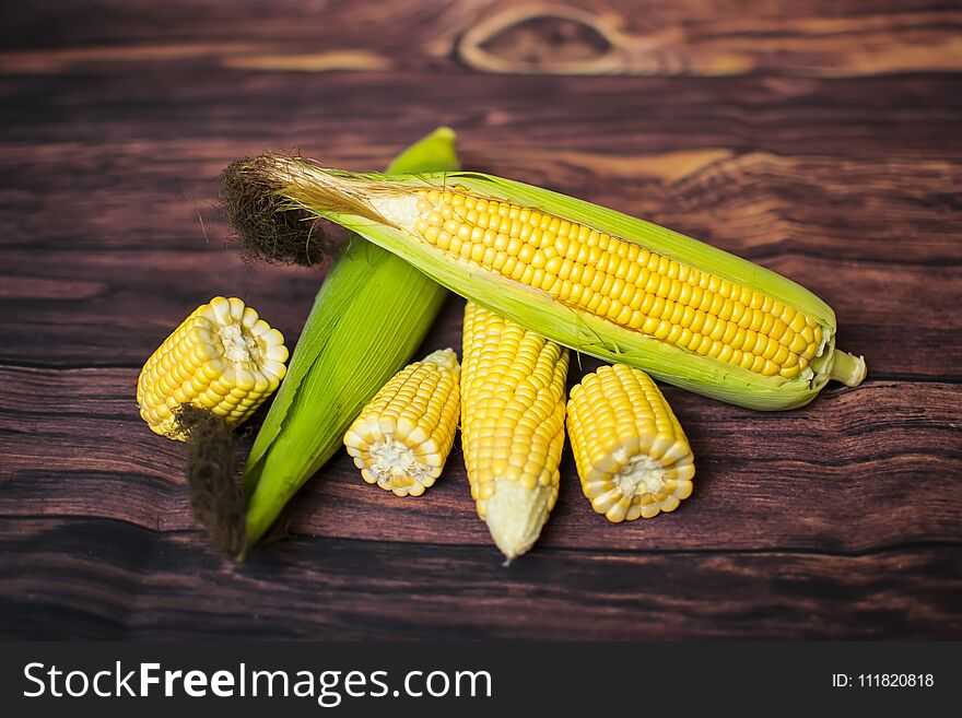 Fresh corn on cobs on wooden table, closeup, top view.