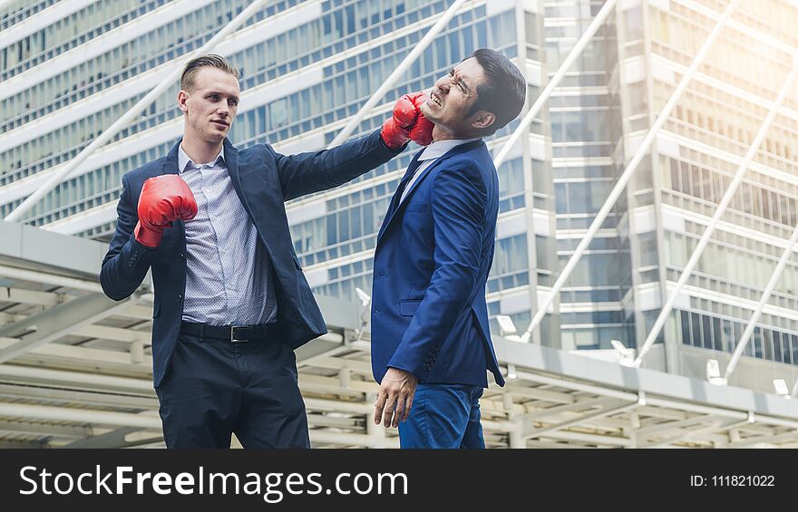 Two business mans are fighting with boxing glove at outdoor city