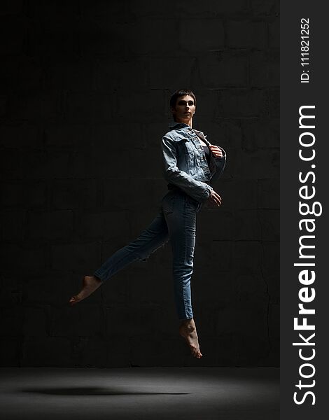 Ballet dancer in jeanswear jumping in dark room