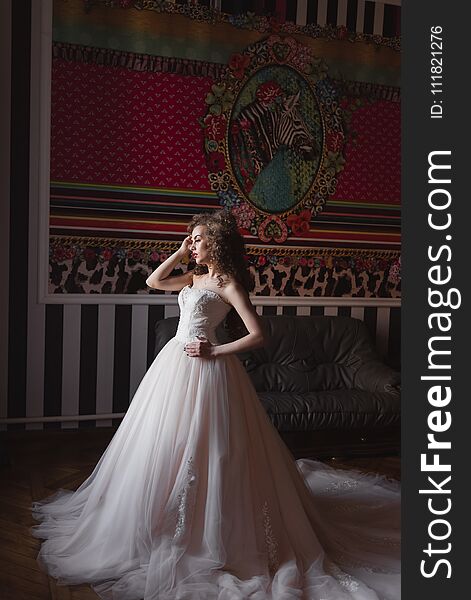 Curly bride standing in a room dressed in a wedding dress