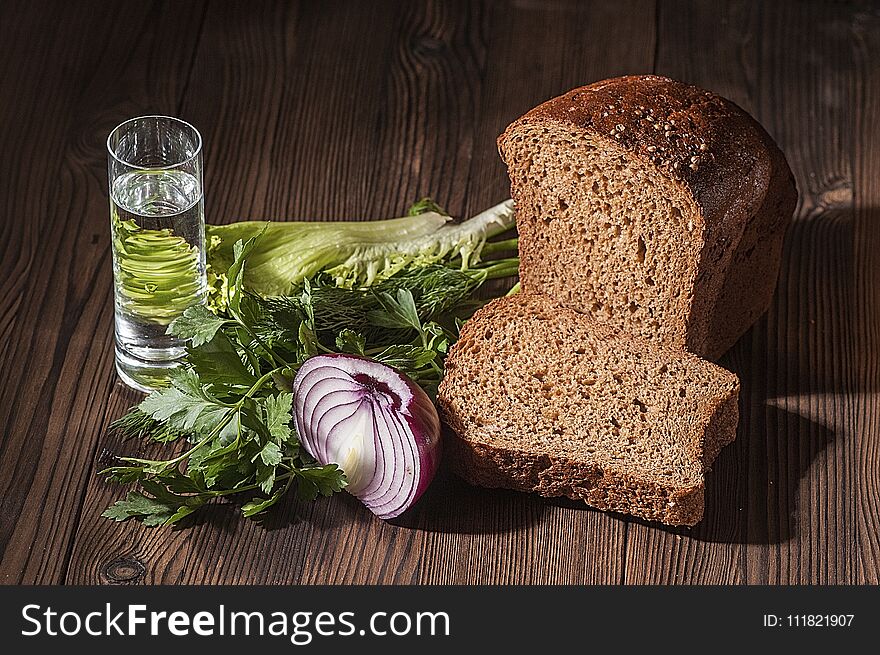 Stack of vodka and a simple snack - greens, half a bulb and a black bread on a dark rustic table. Stack of vodka and a simple snack - greens, half a bulb and a black bread on a dark rustic table