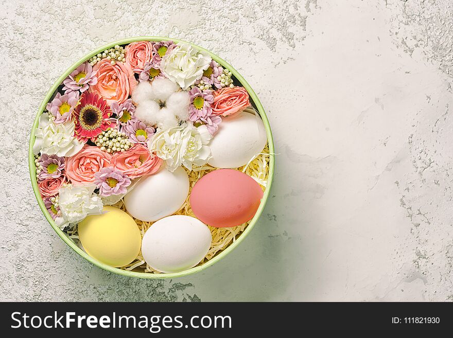 Painted and white easter eggs with flowers in a circle plate on a textured cement background, top view with copy space