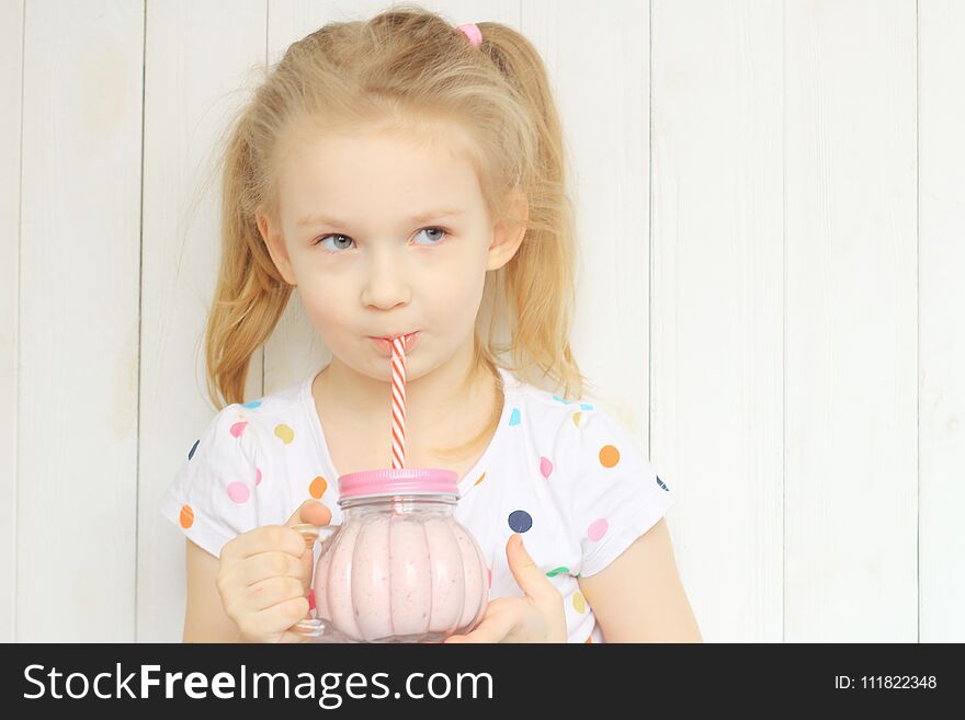 Beautiful girl drinking smoothie shake against white wall