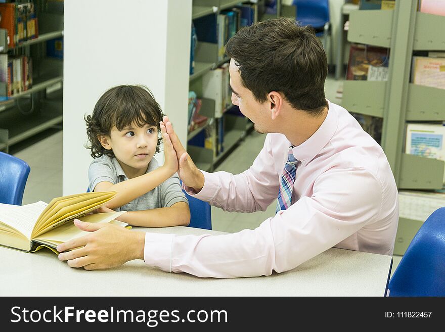 A men teacher and kid student learn with book at bookshelf background