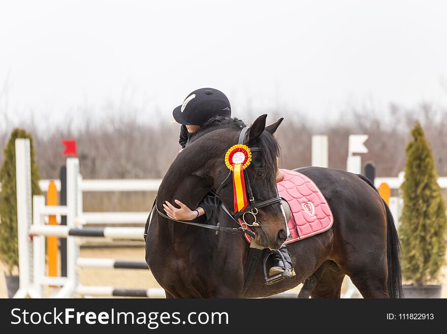 Girl hugging a horse after winning a prize for a show jumping competition. Girl hugging a horse after winning a prize for a show jumping competition.