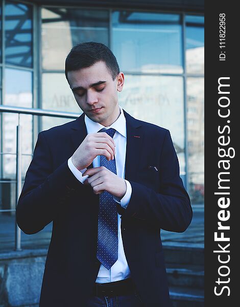 Elegant young fashion man looking at his cufflinks while fixing them