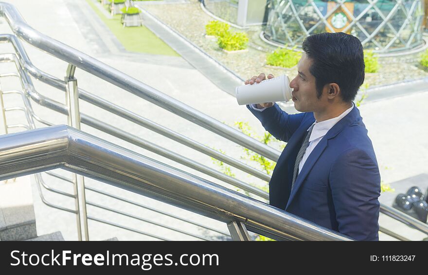 a business asia man drink coffee with paper cup of drink at outdoor