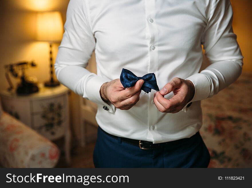 Close-up businessman groom holding bow-tie in his hands. Concept of men stylish elegance clothes.