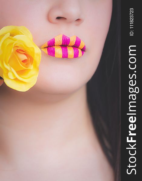 Woman Wearing Yellow and Pink Striped Lipstick Holding Yellow Rose