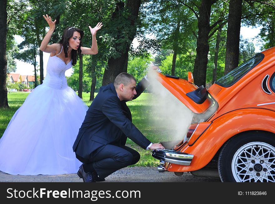 Woman in White Wedding Gown Near Orange Car