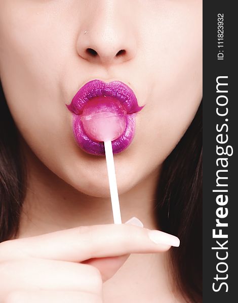 Woman Wearing Purple Lipstick With Pink Lollipop