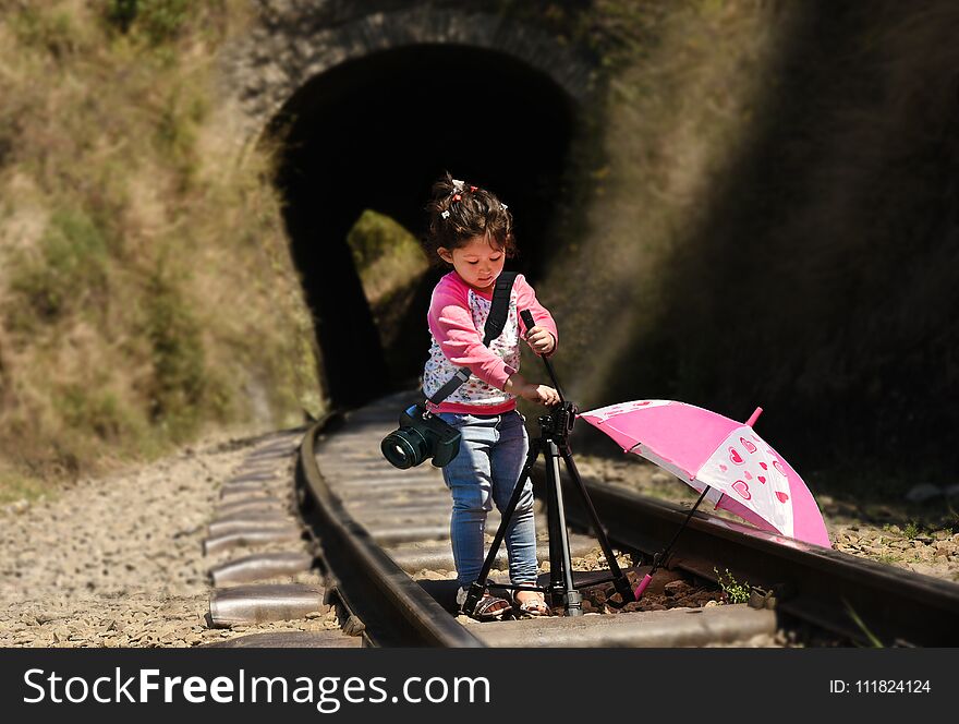 Little girl photographer with tripod and DSLR camera strapped on her neck