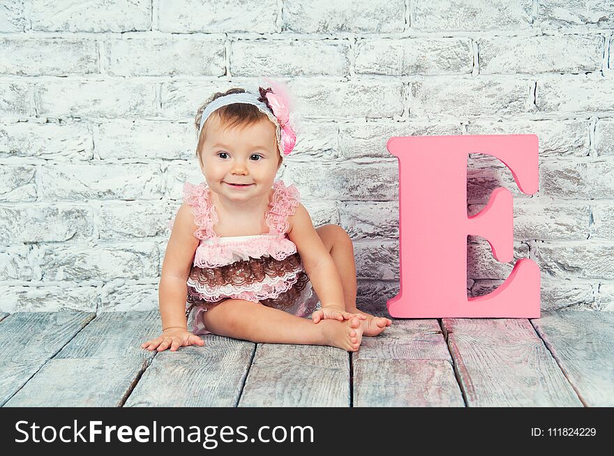 Beautiful And Cute Girl In Pink Dress With The Letter E. Emotional Girl.