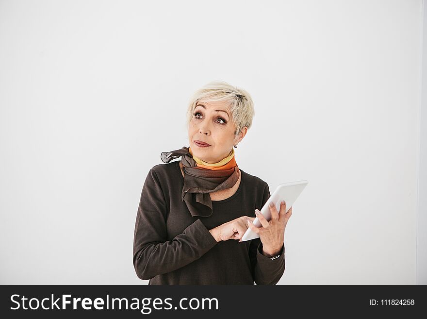 A Positive Modern Elderly Woman Holds A Tablet In Her Hands And Uses It. The Older Generation And Modern Technology.