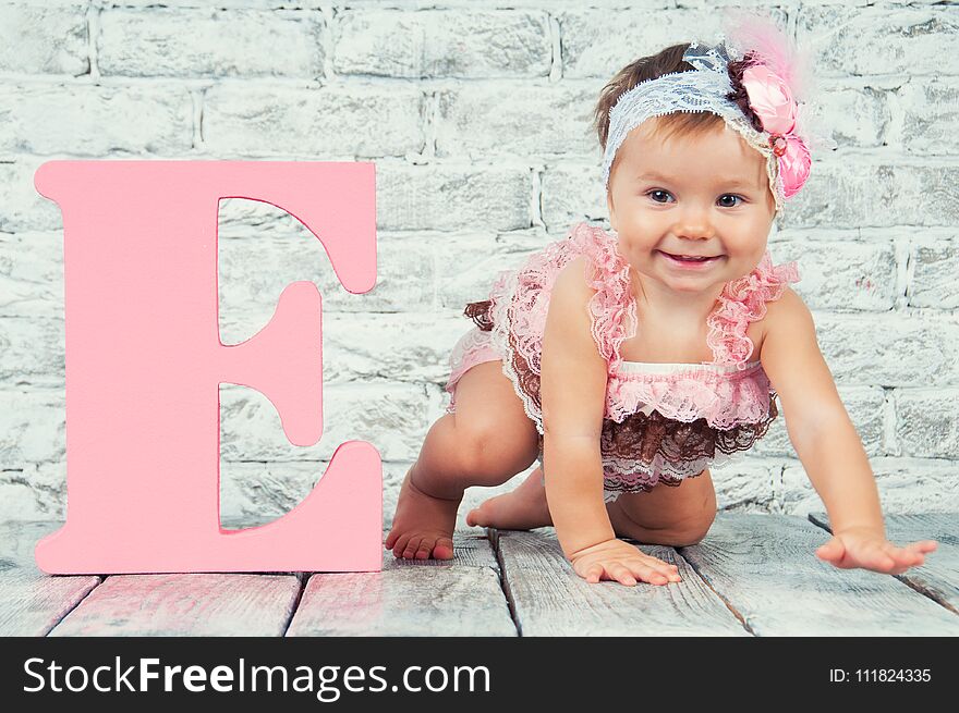 Beautiful and cute girl in pink dress with the letter E. Emotional girl.