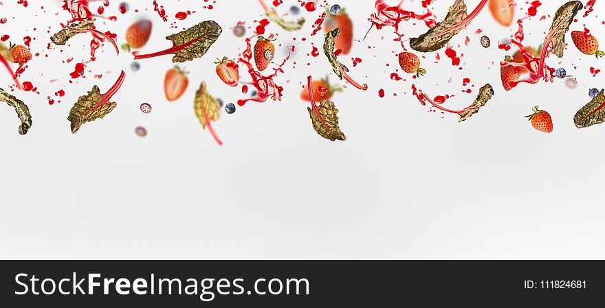 Various flying or falling berries with red chard leaves and splash of juice on white background, banner or template