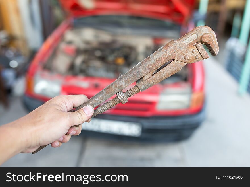 Wrench in hand on the background of cars .