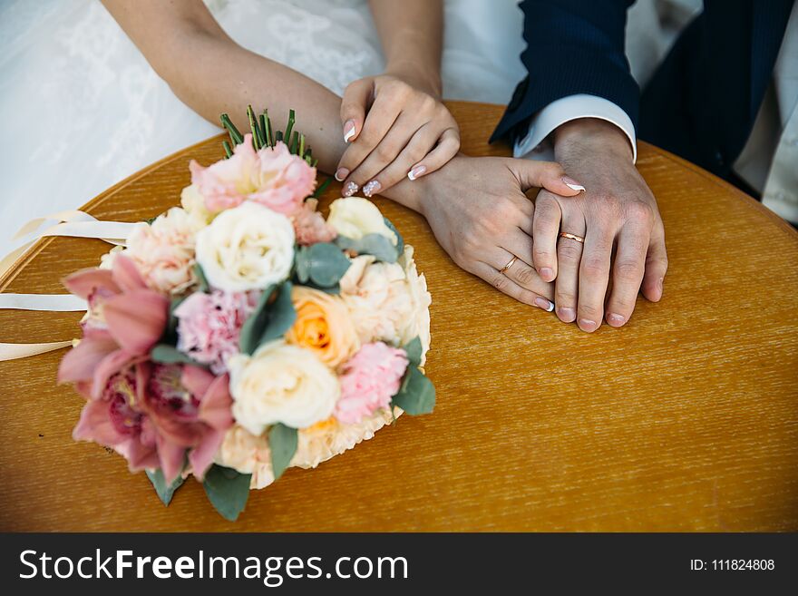 Closeup groom and bride are holding hands at wedding day and show rings. Concept of love family