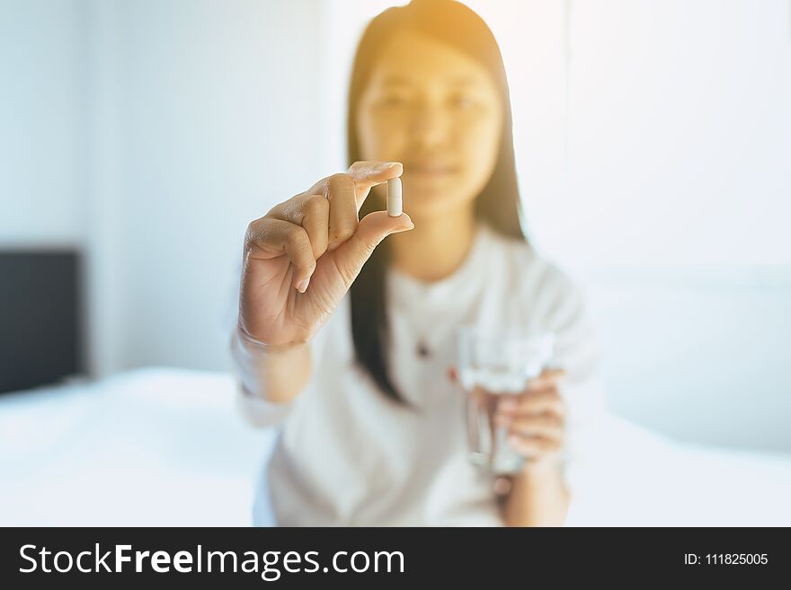 Woman with pills or capsules on hand and a glass of water,Selective focus