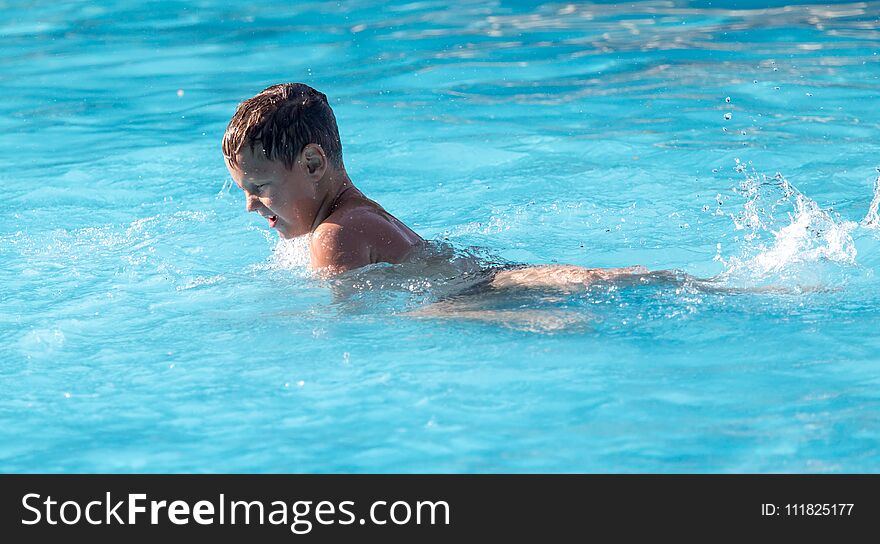 Boy swims with a splash in the water park .